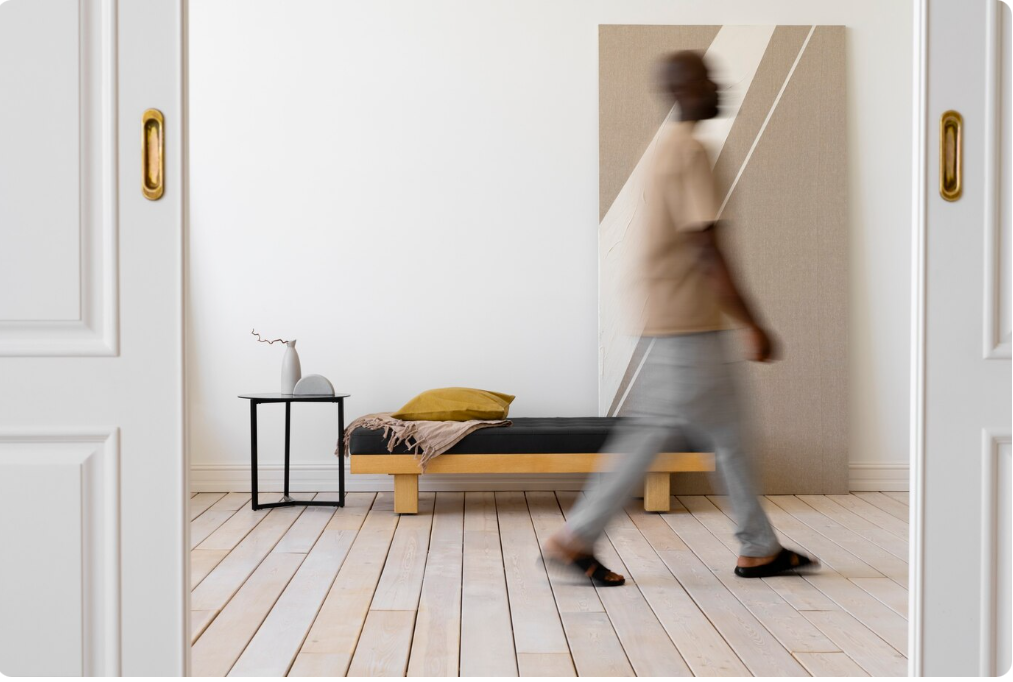 Intérieur moderne aux murs blancs et sol clair, avec un lit de jour en bois et une petite table, illustrant l'effet d'agrandissement du blanc.